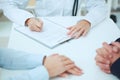 Closeup of patients hands and doctor taking notes. Royalty Free Stock Photo