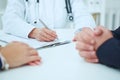 Closeup of patients hands and doctor taking notes. Royalty Free Stock Photo