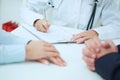 Patients hands and doctor taking notes in patients history. Royalty Free Stock Photo