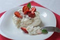 Closeup Pavlova meringue cake with whipped cream, fresh strawberry and mint on white plate. Delicious dessert. Royalty Free Stock Photo