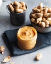 Closeup peanut butter in a glass jar, a handful of peanuts in shell. Foodphoto. Copy space. Breakfast for vegetarians