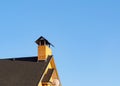 Closeup of peeled brick chimney on the roof under blue sky