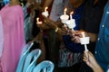 Closeup of people holding candle vigil in dark seeking hope