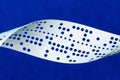 Closeup of perforated punched tape on blue background Royalty Free Stock Photo