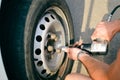 Closeup of person checking fixing bolts on vehicle tire with bare hands. Royalty Free Stock Photo