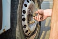 Closeup of person checking fixing bolts on vehicle tire with bare hands. Royalty Free Stock Photo