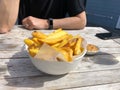 Closeup of a person eating from a bowl of fried potatoes on a wooden table Royalty Free Stock Photo