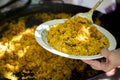Closeup of a person getting a serving of freshly cooked paella