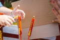 Closeup of person hands lighting red auspicious candle with golden Chinese on candlestick