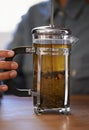 Closeup, person and hands with tea plunger for brewing, heathy and fresh beverage start morning. Cafe, table and prepare Royalty Free Stock Photo