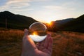 Closeup of a person holding a crystal ball with the surroundings reflecting on it under the sunlight