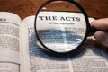 Closeup of a person holding a magnifier and reading the Acts from the New Testament Royalty Free Stock Photo