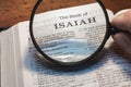 Closeup of a person holding a magnifier and reading the book of Isaiah from the New Testament