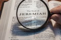 Closeup of a person holding a magnifier and reading the book of Jeremiah from the New Testament