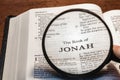 Closeup of a person holding a magnifier and reading the book of Jonah from the New Testament Royalty Free Stock Photo