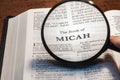 Closeup of a person holding a magnifier and reading the book of Micah from the New Testament Royalty Free Stock Photo