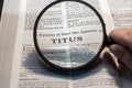 Closeup of a person holding a magnifier and reading the book of Titus from the New Testament Royalty Free Stock Photo