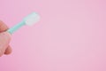Closeup of a person holding a new toothbrush against a pink backgro Royalty Free Stock Photo