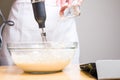 Closeup of a person mixing batter for cheesecake in a bowl on the table