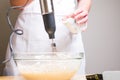 Closeup of a person mixing batter for cheesecake in a bowl on the table