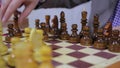 Closeup of person playing chess game on a wooden board in the gameroom