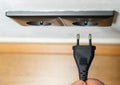 Closeup of a person plugging a cable into a socket on the wall