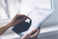 Closeup of a person pointing finger to a computer monitor with a blank screen blue against a background of window horizontal Royalty Free Stock Photo