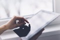 Closeup of a person pointing finger to a computer monitor with a blank screen blue against a background of window horizontal Royalty Free Stock Photo