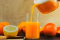 Closeup of a person pouring fresh orange juice in a glass on the table with oranges and lemons on it Royalty Free Stock Photo