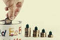 Closeup of a person putting a coin in a coin bank on the table under the lights