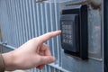 Closeup of a person ringing the gate intercom in the daylight
