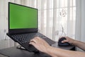 Closeup of a person working on a laptop with green screen space