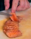Closeup of a person& x27;s hand cutting fish with knife on a board Royalty Free Stock Photo