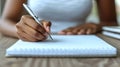 Closeup of a persons hand writing in a spiral notebook. The image conveys focus, concentration, and the process of creation or Royalty Free Stock Photo