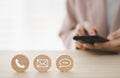 Closeup phone, chat, mail icon on round wooden piece with woman using smart phone on background