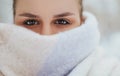 Beautiful brunette female face half covered with winter knitted scarf Royalty Free Stock Photo