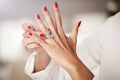 Closeup photo of a beautiful female hands with red nails and elegant diamond rings.