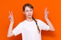 Closeup photo of beautiful little braided hair girl arms showing v-sign symbol hi friends good mood wear white t-shirt