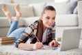 Closeup photo of beautiful young lady student browsing notebook lying floor listen watch lesson online writing notes Royalty Free Stock Photo