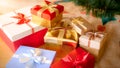 Closeup image of big pile of colorful Christmas gift boxes tied with ribbons lying on floor at living room Royalty Free Stock Photo