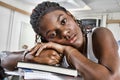 Closeup portrait of bored young African American student resting on stack of books in classroom Royalty Free Stock Photo
