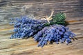 Closeup photo of a bouquet of lavender, tied with a rough rope, lying on another bouquet of lavender on a wooden background witho