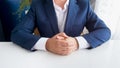 Closeup photo of businessman in blue suit sitting behind white wooden office desk Royalty Free Stock Photo