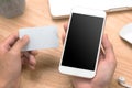 Closeup photo businessman holding hand credit card and using smartphone. Online payments plastic card. Horizontal mockup. Blurred