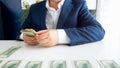 Closeup image of businessman sitting behind desk and laying stack of money in front of him