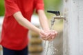 Closeup photo of child washing hands in a city fountain. Little boy drinking clean water from a street pump