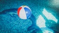 Closeup photo of colorful striped inflatable beach ball floating on the water surface at swimming pool Royalty Free Stock Photo