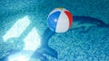 Closeup photo of colorful striped inflatable beach ball floating on the water surface at swimming pool Royalty Free Stock Photo