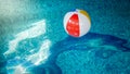 Closeup photo of colorful striped inflatable beach ball floating on the water surface at swimming pool Royalty Free Stock Photo