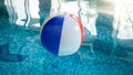 Closeup photo of colorful striped inflatable beach ball floating on the water surface at swimming pool Royalty Free Stock Photo